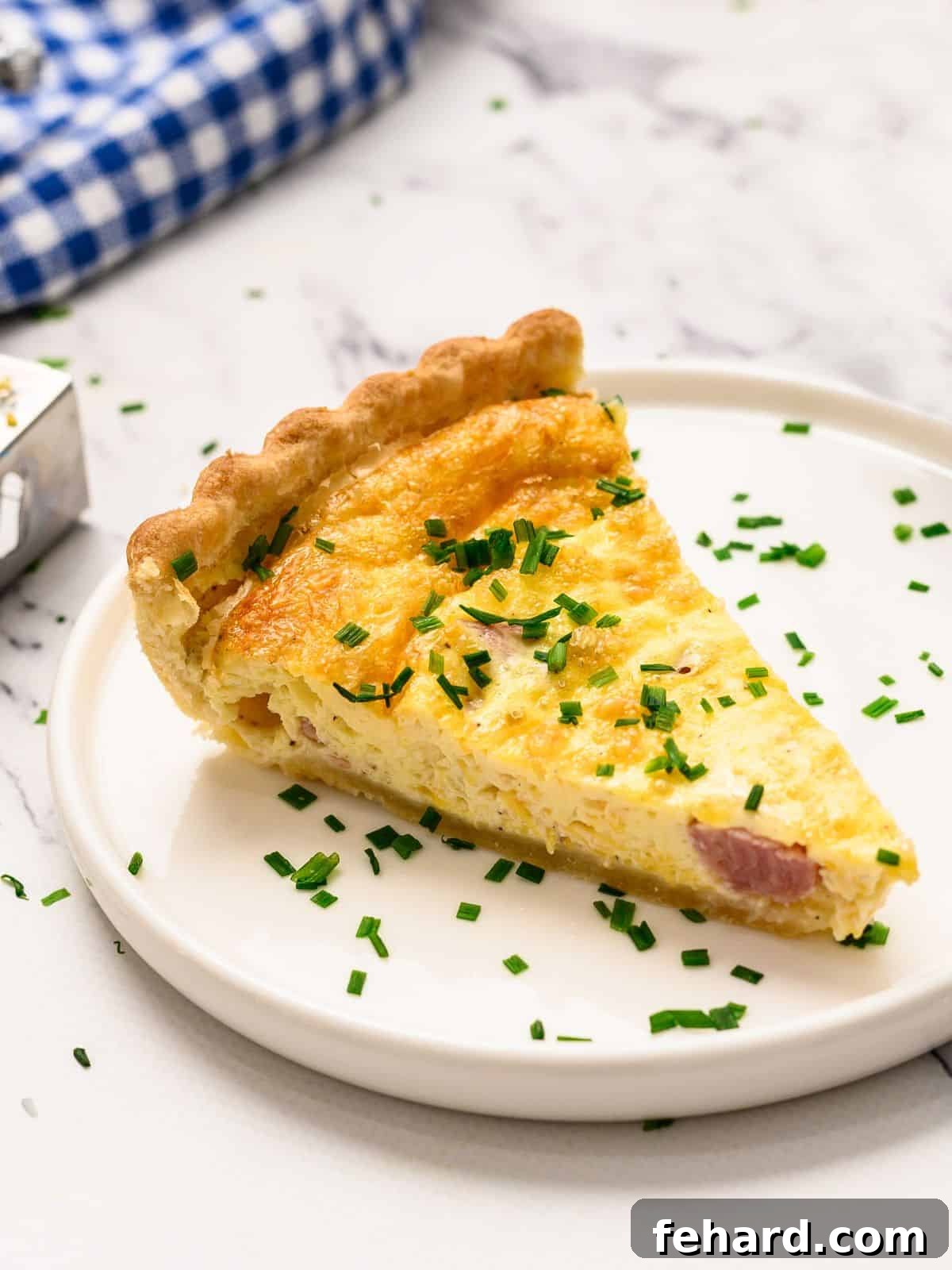 Classic Quiche Recipe A beautifully presented slice of homemade quiche, garnished with fresh chopped chives, rests on a pristine white plate.