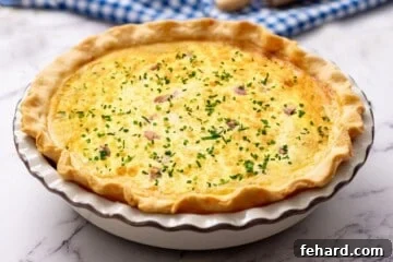 A freshly baked quiche in a pie plate, topped with chopped chives, showcasing its golden crust and set filling.