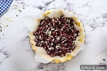 Pie crust lined with parchment paper and dried beans for blind baking.