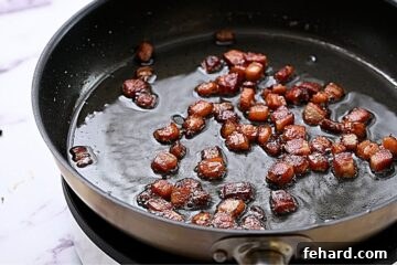 Crispy rendered bacon in skillet, ready to be removed.