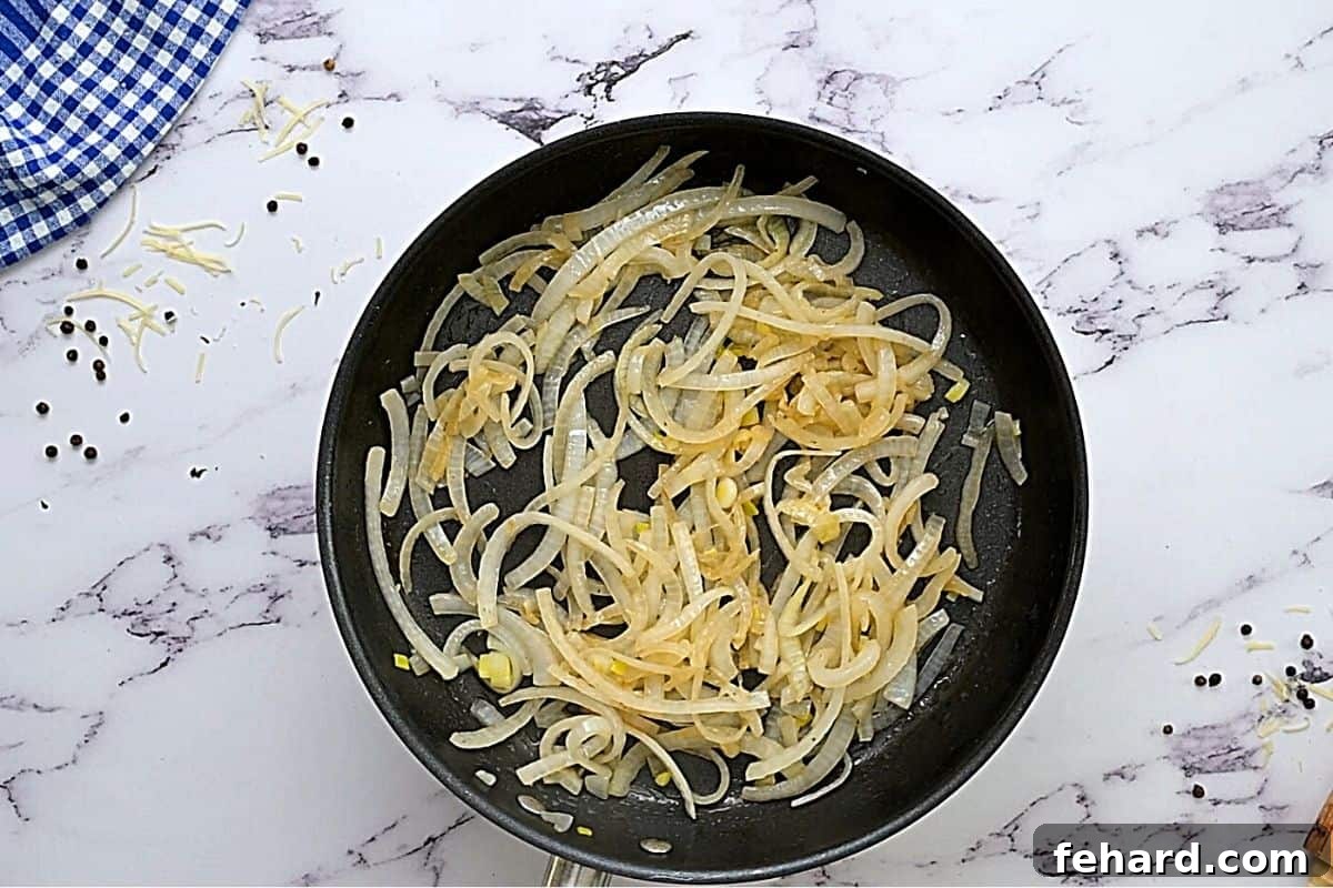Sweet caramelized onions glistening in a skillet with residual bacon fat.