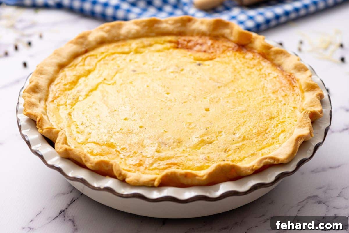 Beautifully baked Quiche Lorraine in a white ceramic pie dish, golden brown and puffed.