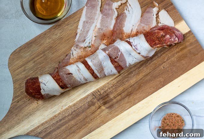 Bacon being wrapped around pork tenderloin, illustrating the technique.