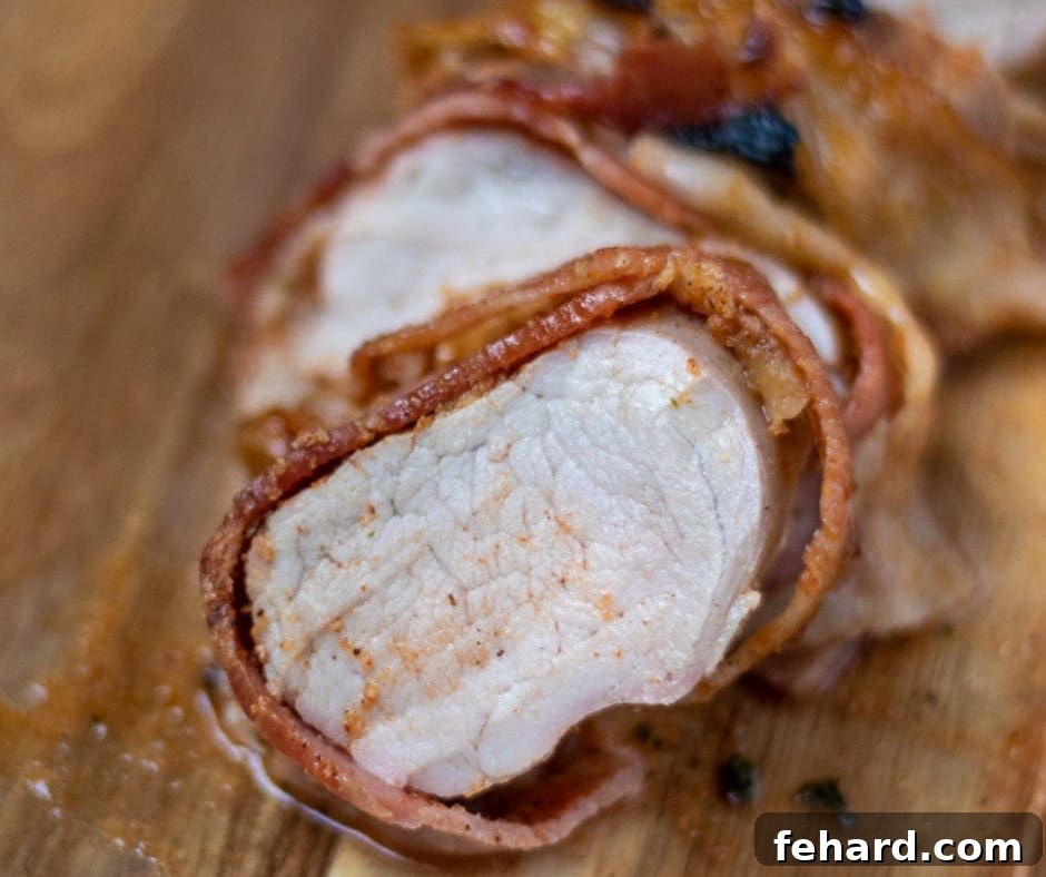 Sliced Pork Tenderloin that has been wrapped in bacon, showing the juicy cross-section.