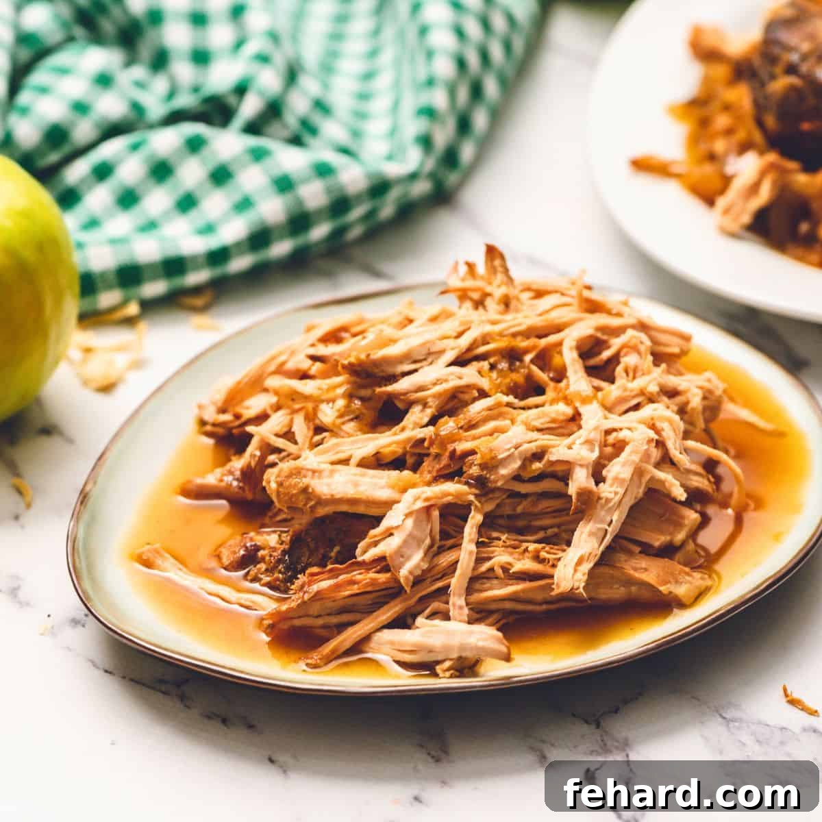 Best Pork and Sauerkraut Recipe Shredded pork loin that has been cooked in apple juice with onions and apples on platter, garnished with fresh parsley.