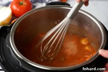 Whisk whisking in cornstarch slurry into stew inside inner pot of instant pot.