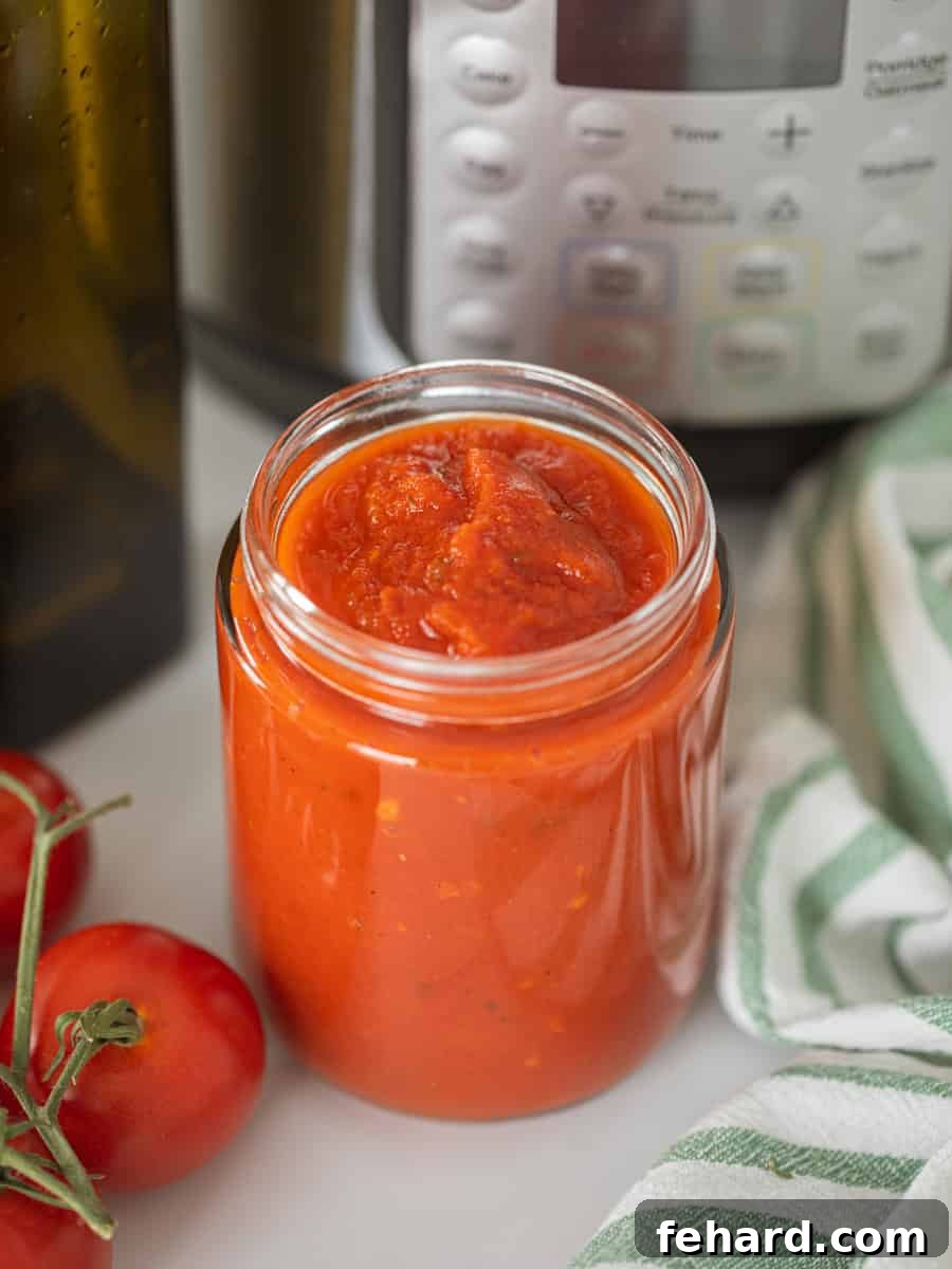 Instant Pot Spaghetti Sauce Jar of homemade spaghetti sauce next to Instant Pot and fresh tomatoes, showcasing a rustic kitchen setting.