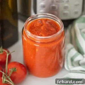 Instant Pot Spaghetti Sauce in clear glass jar next to Instant Pot and fresh tomatoes.