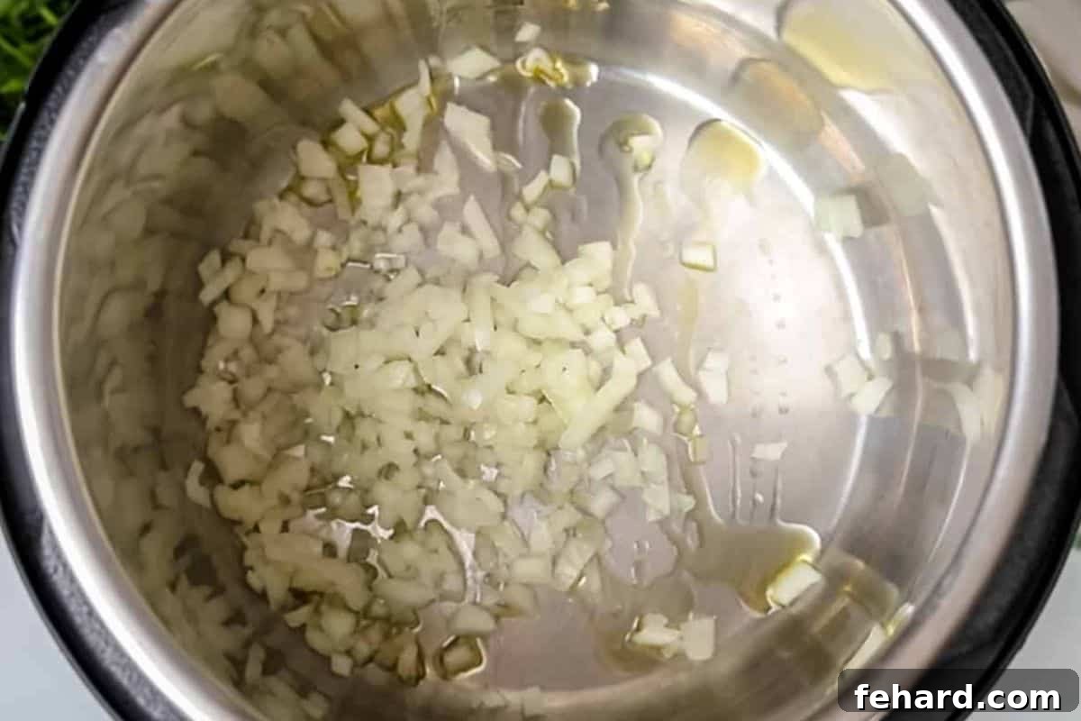 Instant Pot Spaghetti Sauce Recipe Minced yellow onions sautéing in olive oil in the inner pot of an Instant Pot.