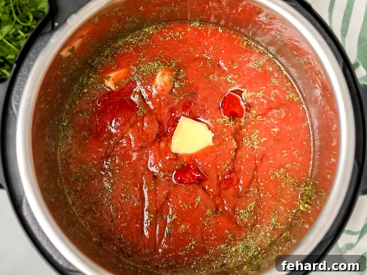 Instant Pot Tomato Sauce Layers of ingredients for spaghetti sauce in an Instant Pot before pressure cooking, with broth at the bottom and tomatoes on top.