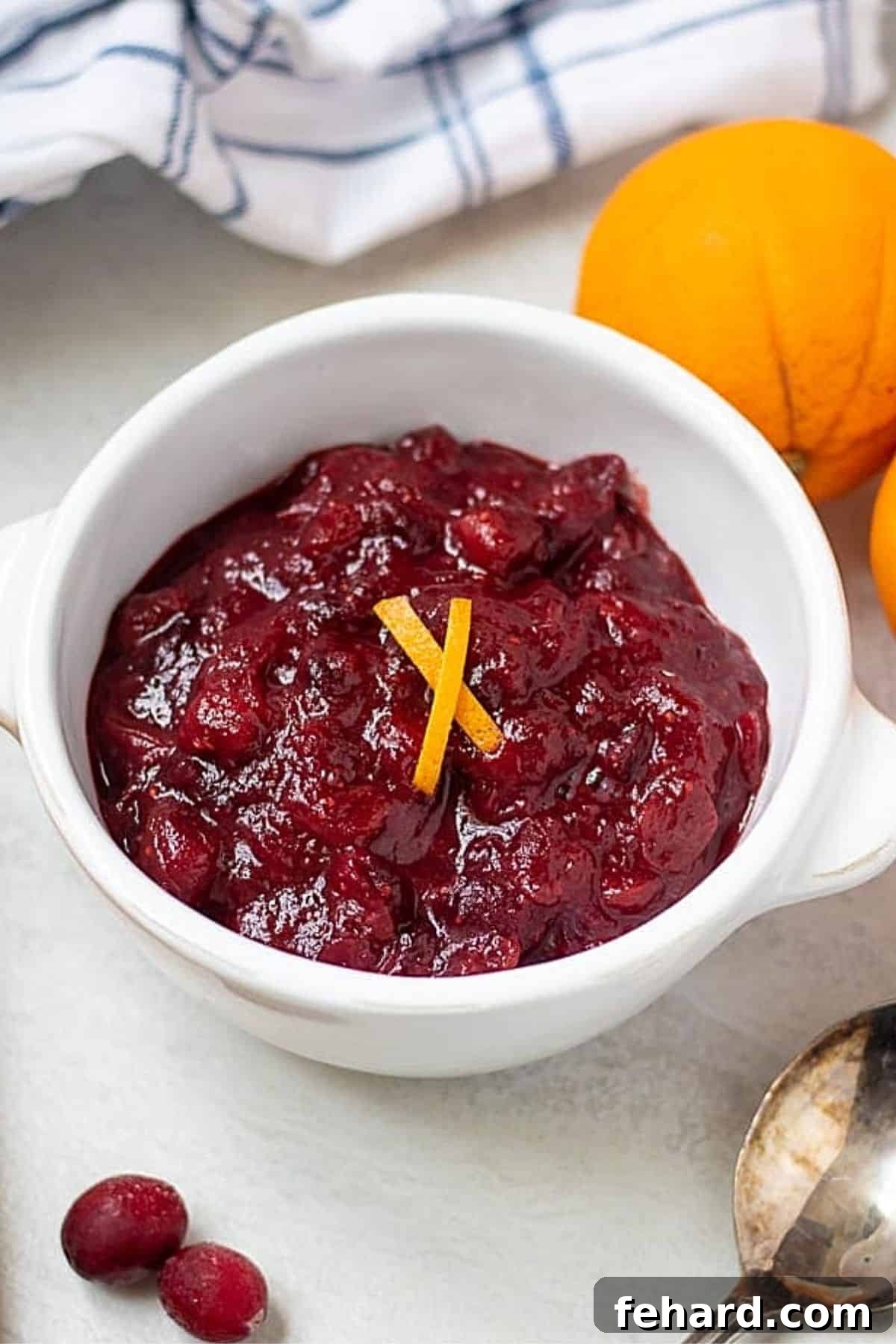 A beautiful bowl of Homemade Cranberry Orange Sauce, garnished with fresh orange zest and a few whole cranberries, ready to be served.
