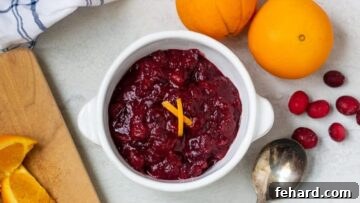 Cranberry Sauce with orange slices on wooden cutting board.