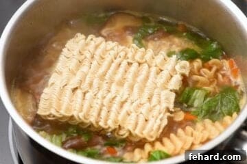 Ramen noodles cooking in broth.