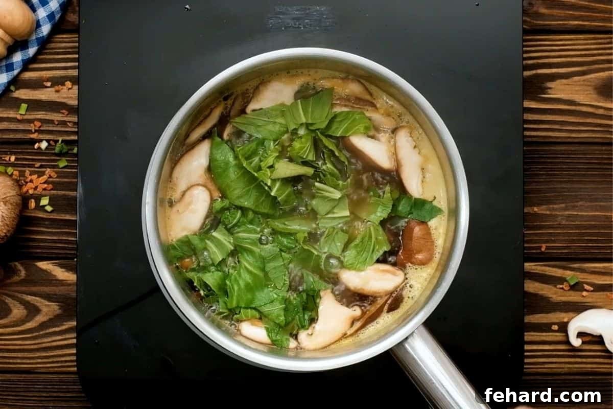 Vegetarian Ramen Recipe Colorful vegetables, including mushrooms and bok choy, simmering in the aromatic ramen broth in a saucepan.
