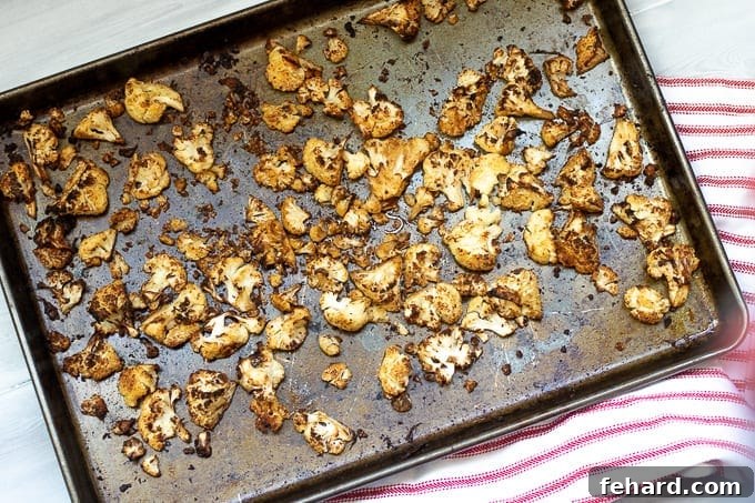 Roasted Cauliflower Tacos A sheet pan generously loaded with vibrant Mexican-spiced roasted cauliflower florets, showcasing their golden-brown edges and aromatic seasoning, ready to be transformed into delicious tacos.