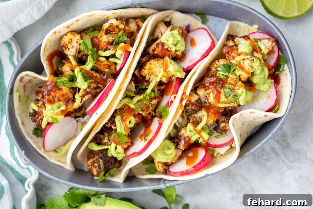 Roasted Cauliflower Taco Recipe Two vibrant roasted cauliflower tacos artfully arranged on soft tortillas, generously topped with a swirl of creamy avocado sauce, fresh radish slices, and cilantro, promising a delightful culinary experience.