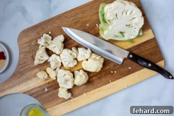 Cauliflower on chopping board cut into florets.