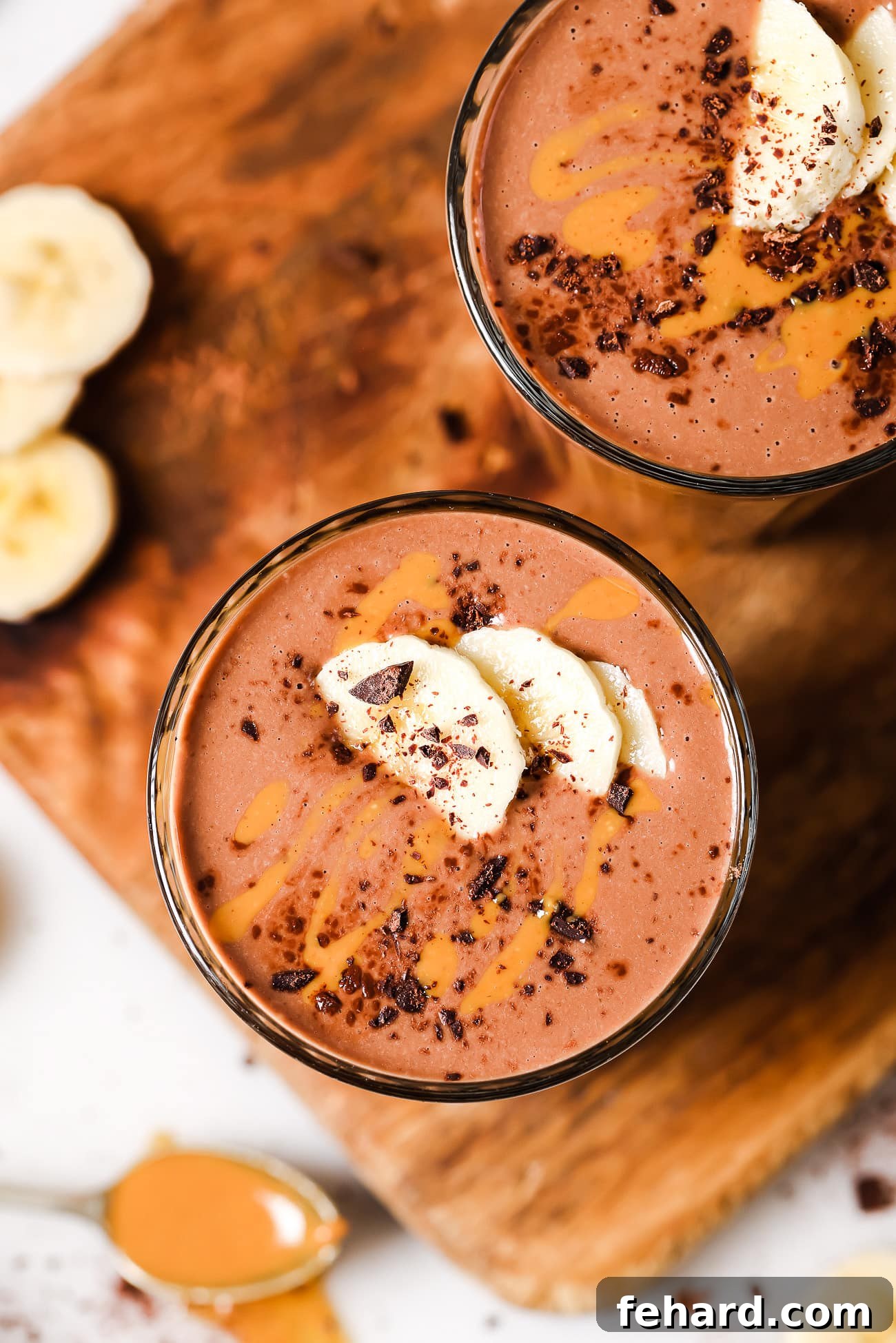 An overhead view of a peanut butter chocolate smoothie, expertly garnished with fresh banana slices and a light sprinkle of cocoa powder.