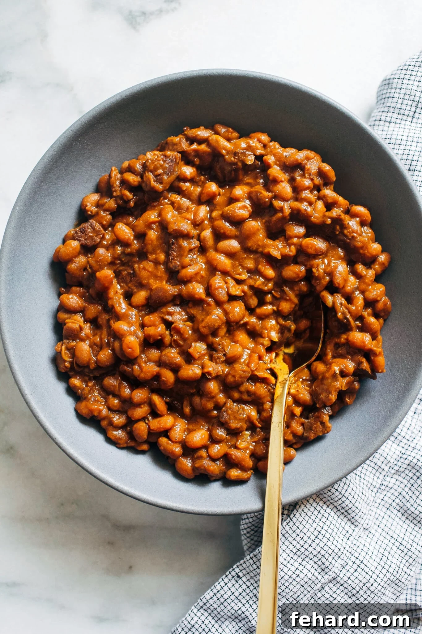overhead view of a bowl of baked beans, rich and saucy, ready to be enjoyed.