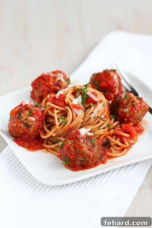 Slow Cooker healthy spaghetti and meatballs in a bowl, topped with parmesan and fresh basil.