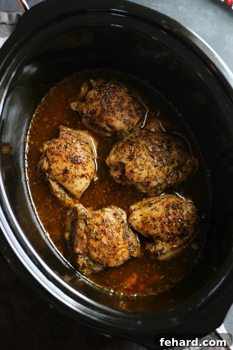 overhead view of a slow cooker pot containing flavorful jerk chicken, ready to be pulled.