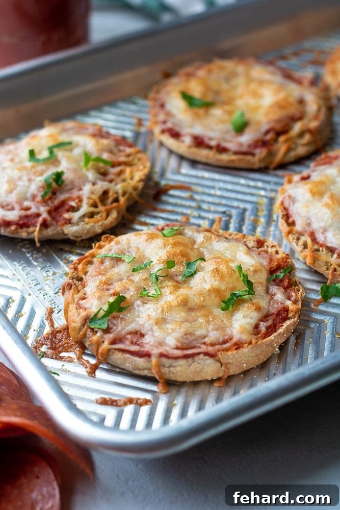 Metal Tray with Baked Cheese English Muffin Pizzas, golden and bubbly.