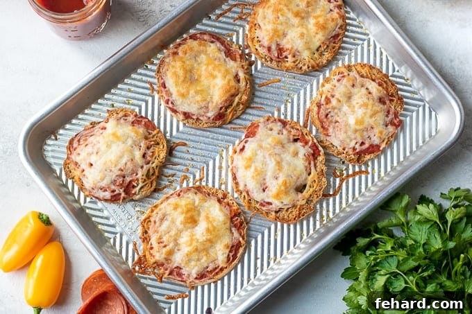Baked English Muffin Pizzas with melted cheese and toppings on a metal sheet pan, ready to serve.