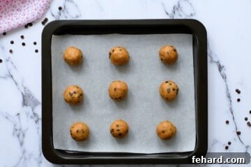 The Legendary Billion-Dollar Cookie Recipe 7 9 rolled cookie dough balls on a parchment lined baking sheet.