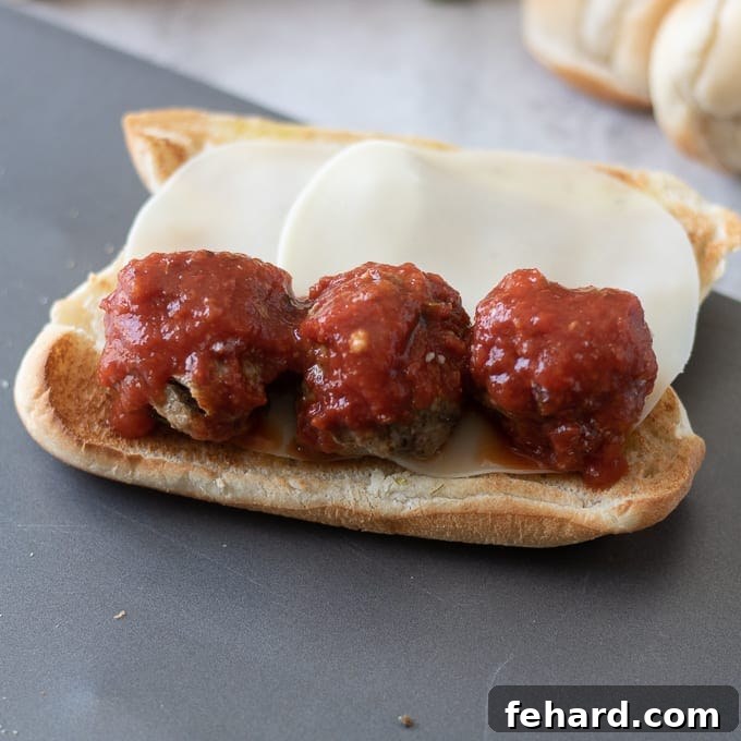 Best Meatball Sub: Arranging the meatballs Three perfectly placed meatballs on a sub sandwich, ready for more cheese.