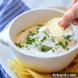 Wavy Potato Chip Scooping up some homemade chip dip from a serving bowl.