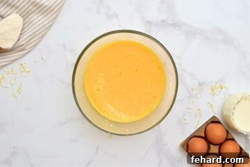 Eggs, cottage cheese, cheddar and green chiles mixed together in large mixing bowl.