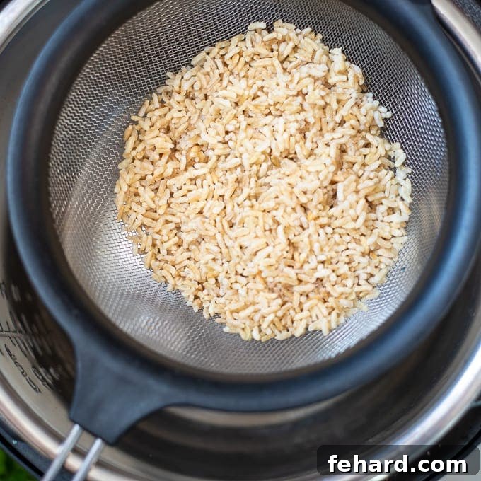 Rinsed rice in a colander, draining over an Instant Pot insert.