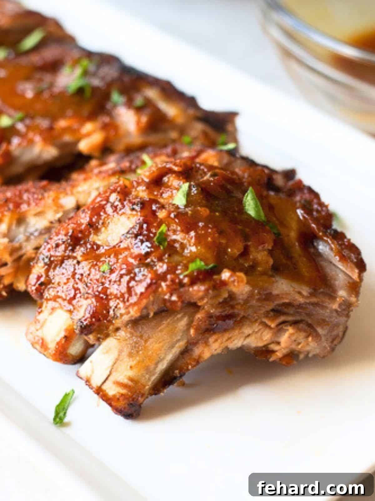 Instant Pot Ribs on white platter next to Instant Pot after being brushed with BBQ sauce and broiled.