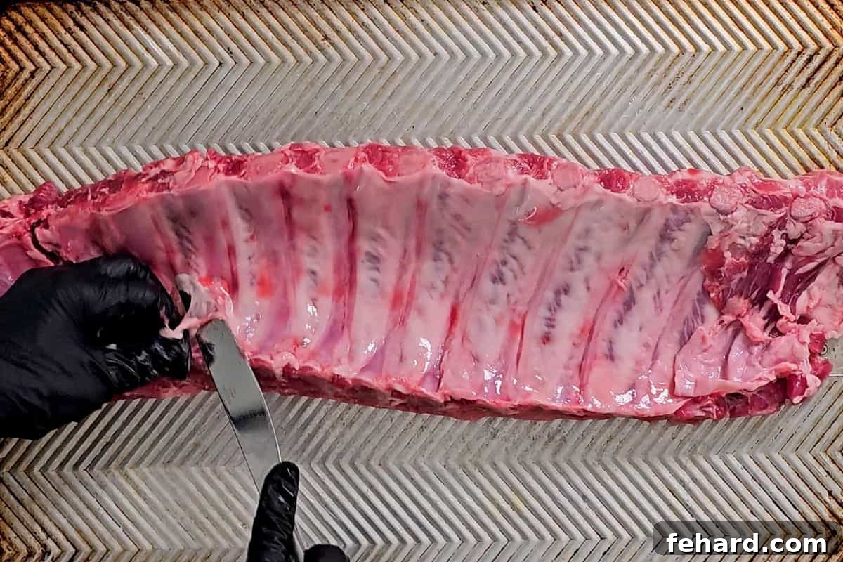 Butter knife sliding under ribs to remove membrane under ribs.
