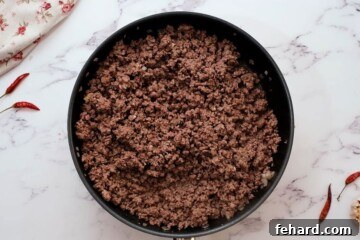 Ground beef, onion, and garlic sautéed in skillet, an essential first step for flavor development in chili.