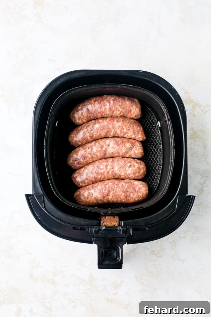 Italian sausages laid out in a single layer inside an air fryer basket, ready for cooking.