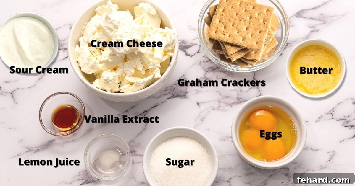 The Best Cheesecake Recipe Ingredients Labeled ingredients for making cheesecake arranged on a white kitchen counter, including cream cheese, eggs, and sour cream.
