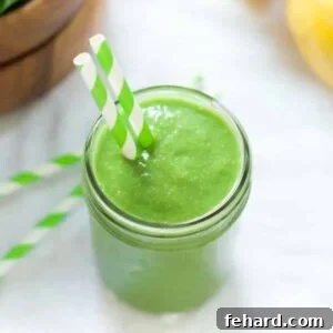 overhead view of a green smoothie in a mason jar with a straw