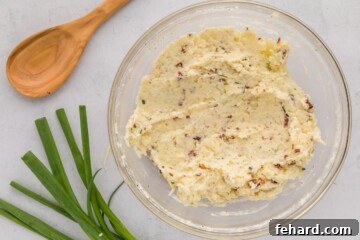 A mixing bowl filled with creamy potato filling, including cheese, bacon, sour cream, butter, and chives.