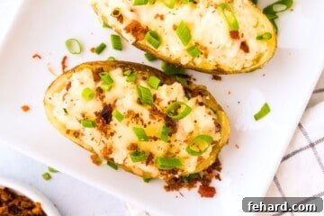 A twice-baked potato garnished with white cheddar, bacon, and green onions, served on a white plate.
