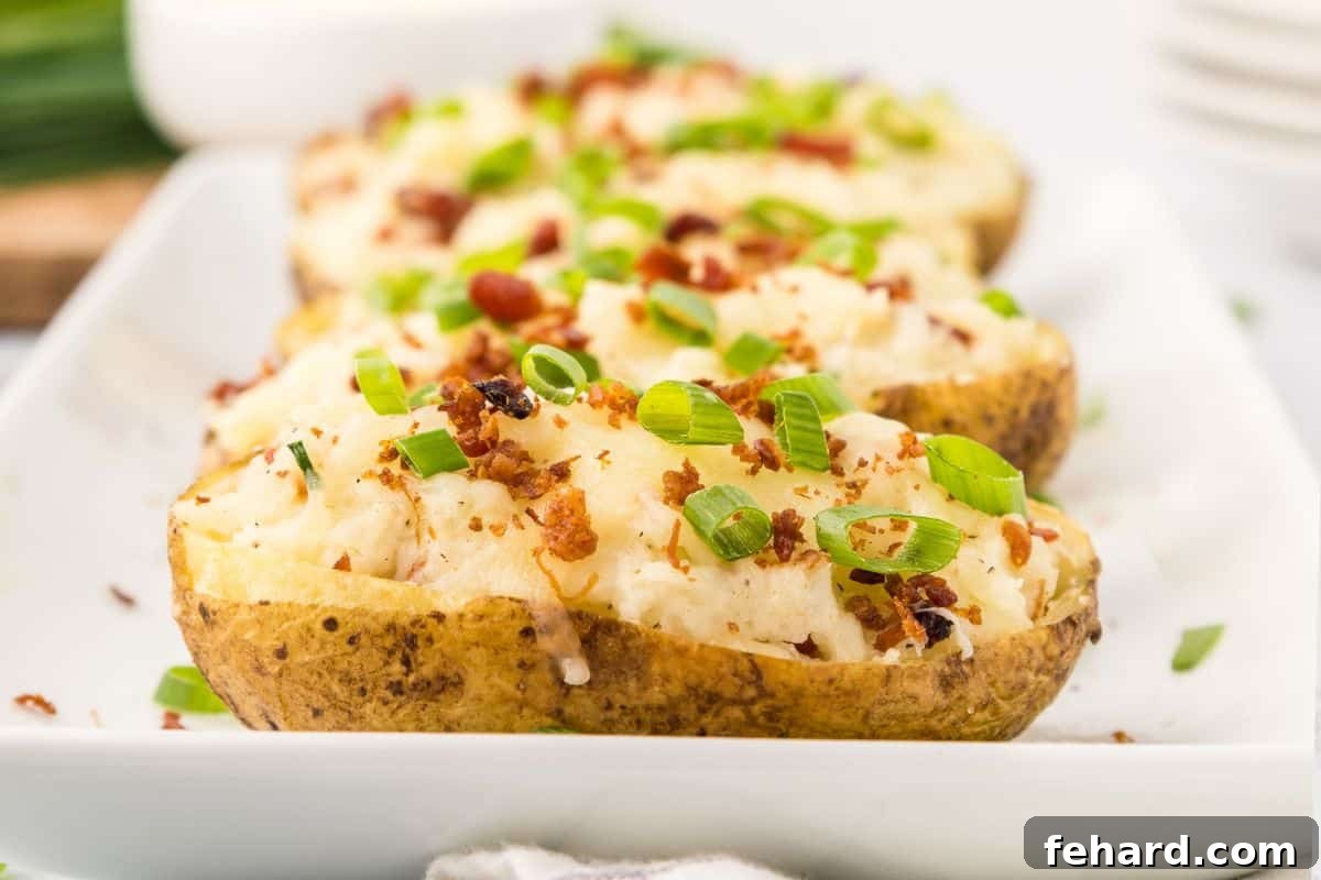 A platter of golden-brown Twice-Baked Potatoes, garnished with crumbled bacon and sliced green onions, ready to be served warm.