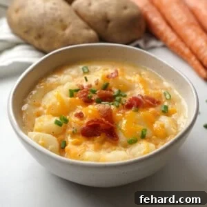 Bowl of instant pot baked potato soup topped with cheese, bacon and chives.