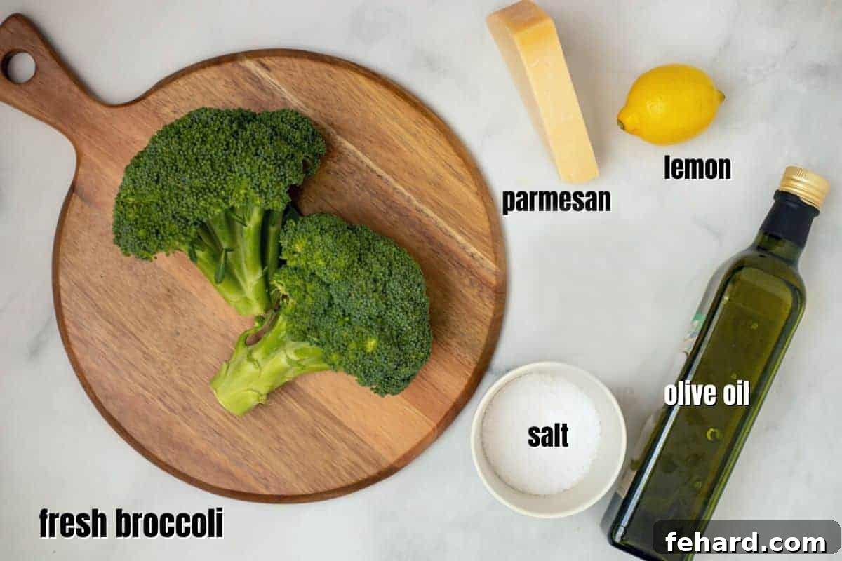 Ingredients for roasted broccoli laid out on a kitchen counter: fresh broccoli, olive oil, parmesan cheese, and a lemon.