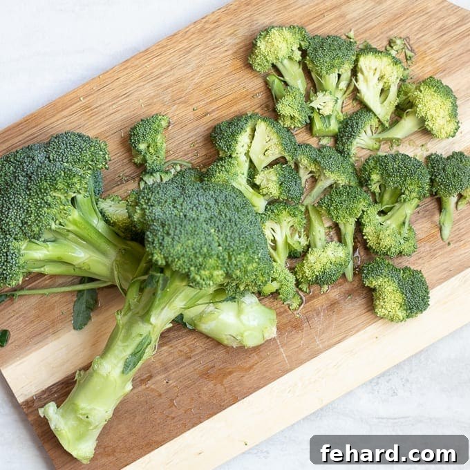 Cutting Board with freshly chopped broccoli florets, ready for seasoning.