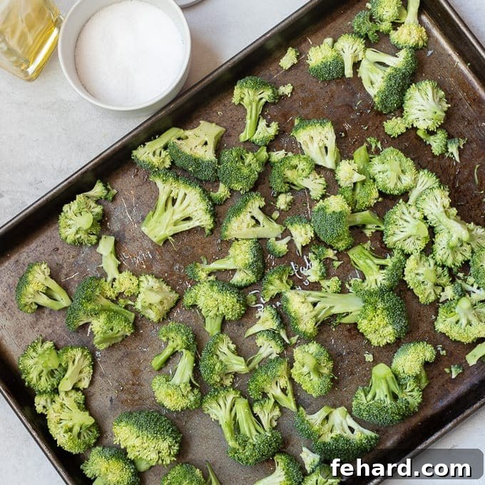 Seasoned broccoli florets spread out in a single layer on a roasting pan.