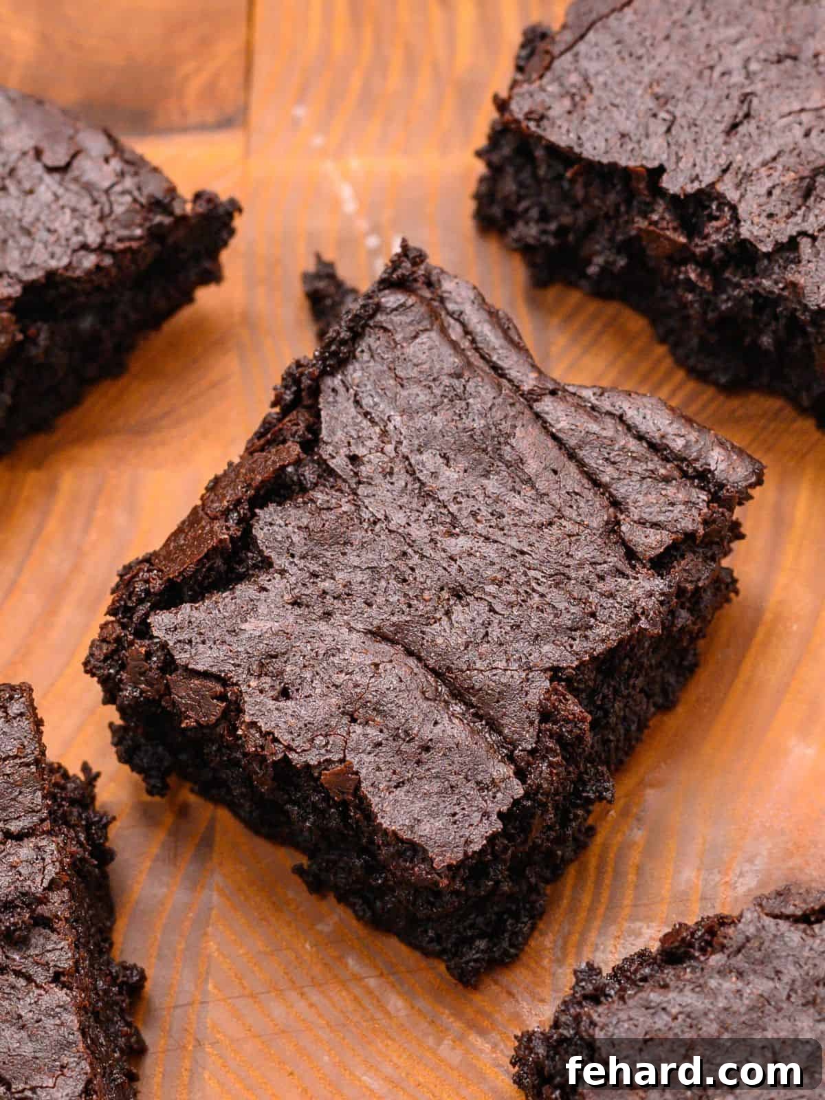 Homemade Ghirardelli Brownies Sliced fudgy brownies on wooden cutting board with chocolate chips scattered around.