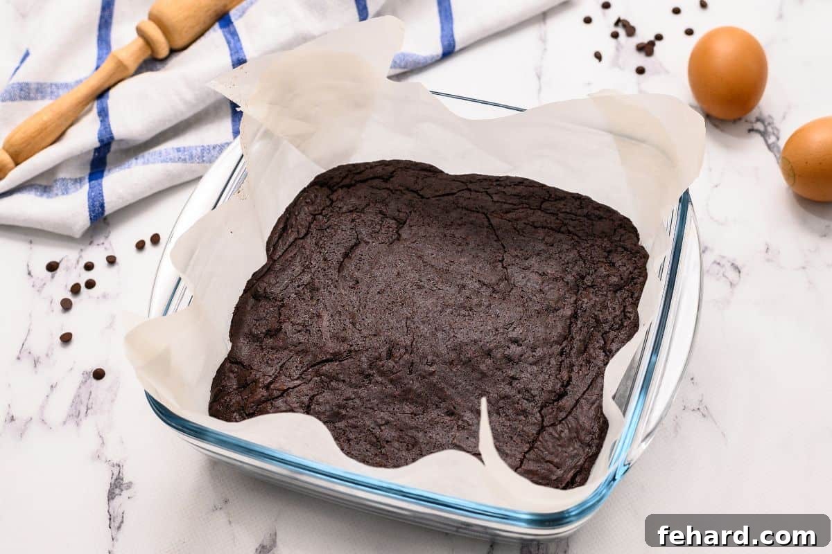 Ghirardelli Brownie Recipe Baked brownies in glass baking dish lined with parchment paper.