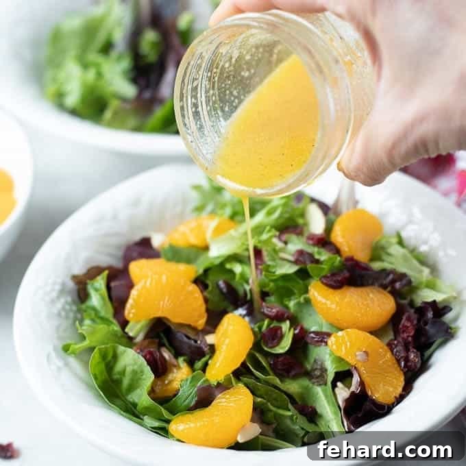 A vibrant Mandarin Orange Salad being drizzled with its homemade citrus dressing.