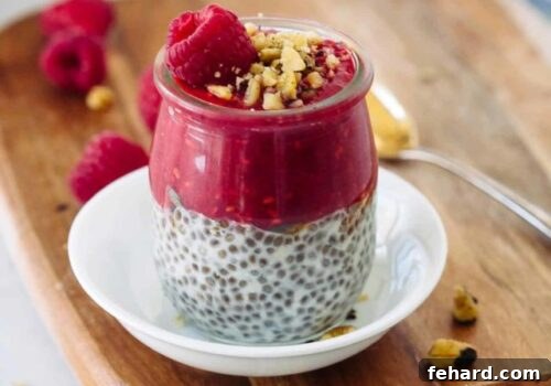 Layered raspberry chia pudding in a glass jar, topped with fresh raspberries and walnuts.