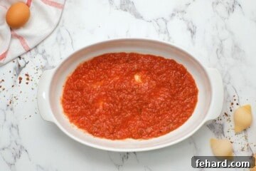 Classic Italian Stuffed Shells 6 Spaghetti Sauce spread out onto a thin layer in oval baking dish, creating a flavorful base.